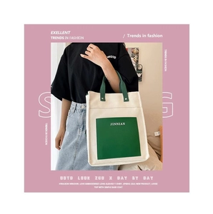 Close-up of beige canvas tote bag featuring a green front pocket with JINNIAN logo