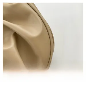 Close-up detail of soft pleated beige leather texture on minimalist shoulder bag