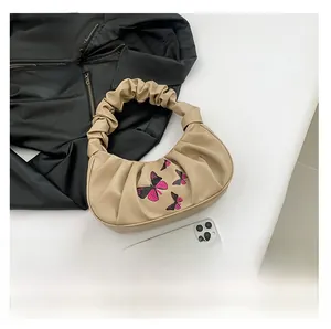 Close-up of beige ruched cloud bag with embroidered butterfly pattern and pleated handle