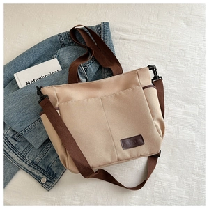 Detail of khaki canvas tote bag with adjustable brown shoulder strap and fashion label