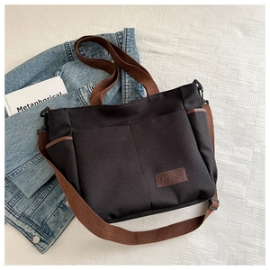 Detail view of black canvas tote bag showing brown straps and FASHION leather label
