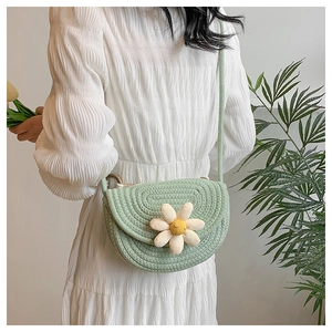 Detail view of woven shoulder bag in light green featuring a daisy flower ornament