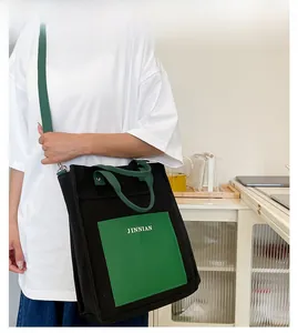 Detail of large-capacity canvas tote bag in black and green with JINNIAN logo print