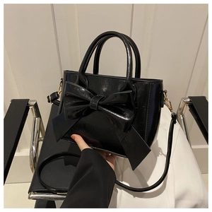 Detail showing glossy patent leather texture and oversized bow design of this handbag