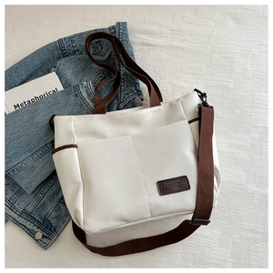 Detailed shot of white canvas tote bag with brown straps and FASHION leather patch