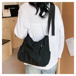 Détail d'un sac hobo en nylon noir avec doubles poches zippées frontales et poches latérales