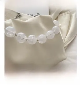 Détail du sac plissé beige avec perles marbrées translucides et chaîne en argent pur