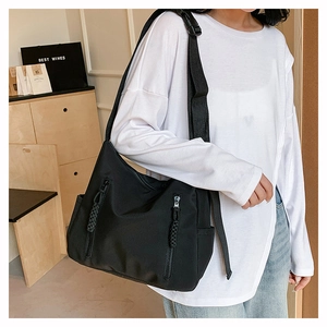 Détail du sac cabas en nylon noir avec poches zippées verticales et tirettes tressées