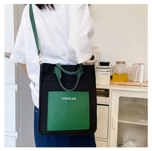 Detail of color-block canvas tote bag with green front pocket and JINNIAN lettering