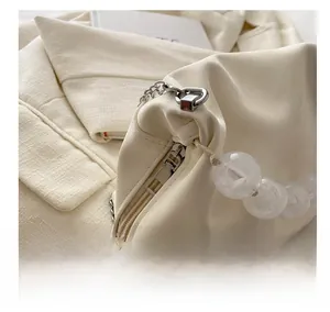 Détail de la fermeture éclair en métal argenté et des perles blanches sur le sac en cuir souple