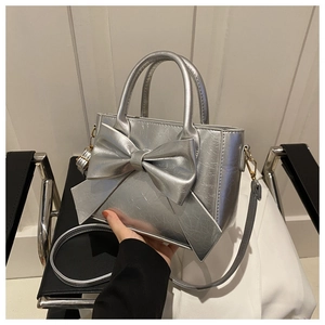 Detail of silver bow handbag with crinkled metallic texture and detachable shoulder strap