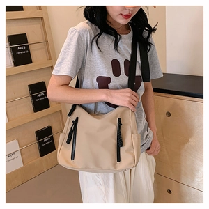 Détail du sac fourre-tout en nylon beige clair avec poches zippées et bandoulière large