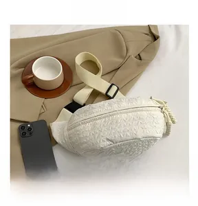 Detail of white textured chest bag with pleated surface and woven zipper pullers