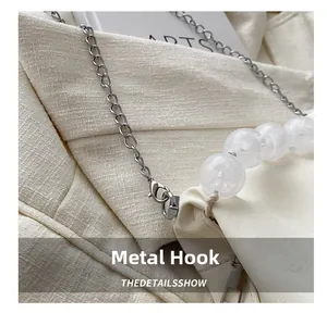 Gros plan détaillé du crochet argenté et de la chaîne de perles du sac en cuir blanc