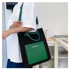 Detail view of large canvas tote bag with contrast green pocket and adjustable strap