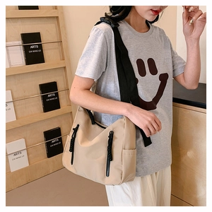 Détail du sac fourre-tout en nylon kaki avec bandoulière noire réglable et poches zippées