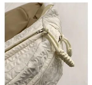Close-up of white embossed textured crossbody bag with silver zipper and knot puller detail