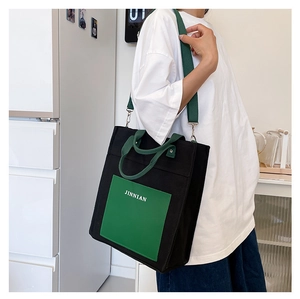 Detailed view of large canvas tote bag with contrast green pockets and shoulder strap