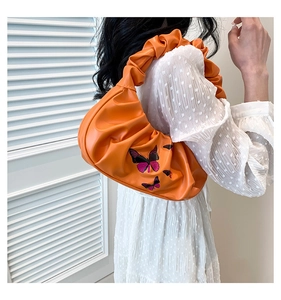 Detail of orange ruched cloud bag featuring purple butterfly print and pleated strap