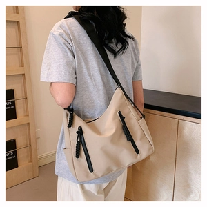 Vue détaillée d'un grand sac cabas en nylon beige avec deux poches à fermeture éclair noires