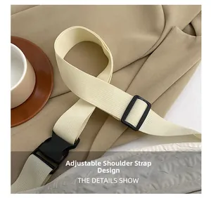 Detail of adjustable nylon strap with black plastic buckle on a beige crossbody bag