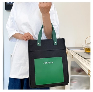 Detail of a large canvas tote bag in black and green with white JINNIAN logo lettering