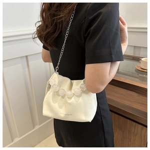 Détail du sac seau ivoire souple avec perles de cristal et logo de la marque embossé