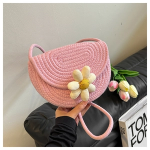 Detailed close-up of a pink woven cotton shoulder bag featuring a cute smiling daisy charm
