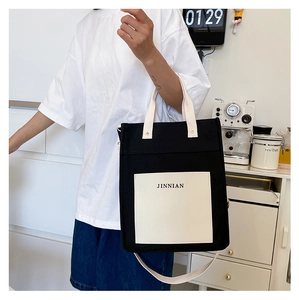 Detail of minimalist canvas tote with white pocket and adjustable strap worn by model