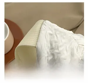 Close-up of white textured fabric and beige woven strap on a minimalist crossbody bag