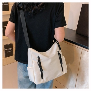 Détail d'un sac cabas en nylon blanc avec zips noirs porté par un mannequin