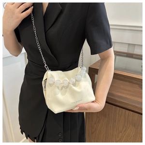 Vue détaillée du sac seau beige avec chaîne argentée et poignée en perles