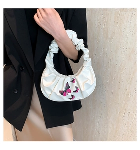 Detail of white cloud bag featuring pink butterfly embroidery and pleated handle