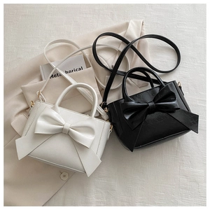 Close-up of bow knot mini handbags in cream and black with grainy PU leather texture