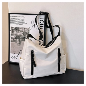 Vue détaillée du grand sac cabas blanc en nylon avec fermetures éclair noires et bandoulière