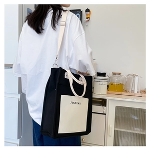 Detail of adjustable strap and JINNIAN logo on a large color-block canvas tote bag