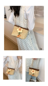 Détail du sac seau en paille tissée avec fleur 3D et bandoulière en chaîne dorée chic