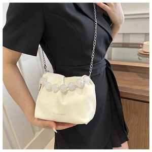 Détail du sac seau crème avec poignée en perles transparentes et chaîne en métal