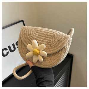 Detail of hand-woven crossbody bag with a large 3D daisy flower and braided strap