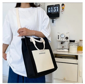Detail of canvas tote bag with contrast cream pocket and adjustable crossbody strap