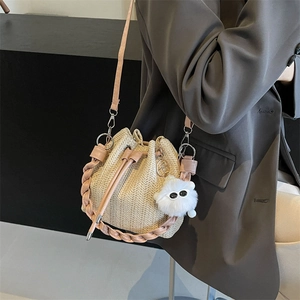 Pink woven straw bucket bag with chain strap and plush charm for summer beach vacation