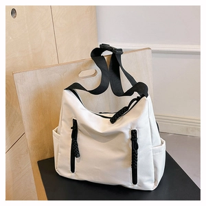 Détail d'un sac fourre-tout en nylon beige avec bandoulière noire et deux poches zippées