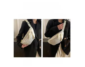 Detail view of cream quilted chest bag with dual zippers and adjustable wide strap