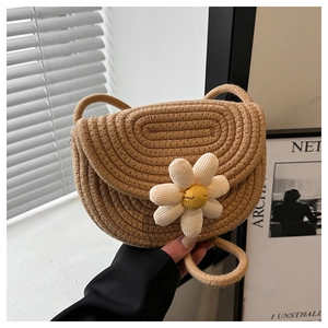 Detail of hand-woven beige crossbody beach bag with a white daisy floral accent