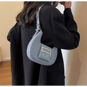Detail view of light blue crescent bag with golden buckle styled on black blazer