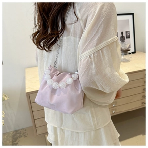 Détail du sac seau en satin rose lavande avec poignée en perles et bandoulière chaîne