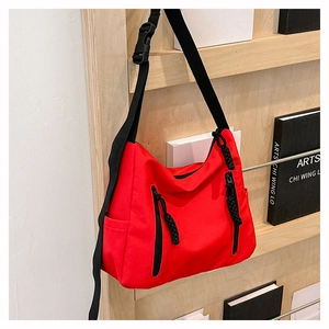 Détail du sac bandoulière en nylon rouge avec fermetures noires et boucle en plastique