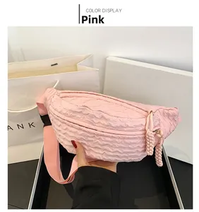 Detailed macro view of pink quilted chest bag with dual zippers and woven knots