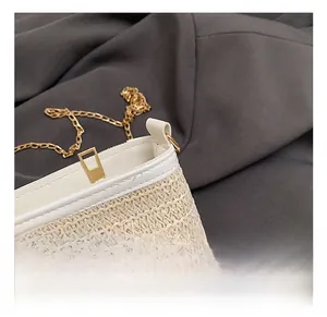 Détail d'un sac seau tressé montrant la chaîne dorée et le fermoir métallique