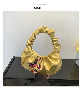 Detailed view of the gold cloud bag featuring purple butterfly print and pleated handle